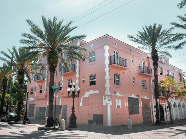 Pink corner building with palm trees and balconies