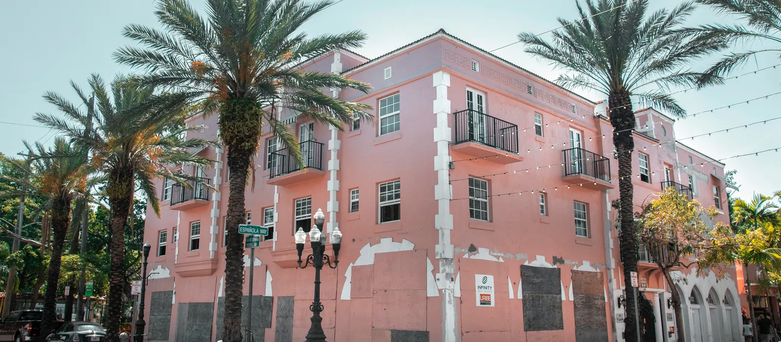 Pink corner building with palm trees and balconies